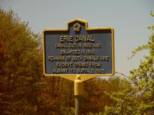 Historical marker for the Erie Canal, detailing its construction in 1822 and enlargement in 1842, with a route from Albany to Buffalo.
