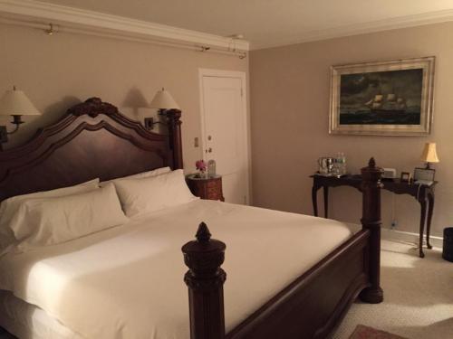 A cozy bedroom featuring a large wooden bed, bedside lamps, and a painting of a ship on the wall.