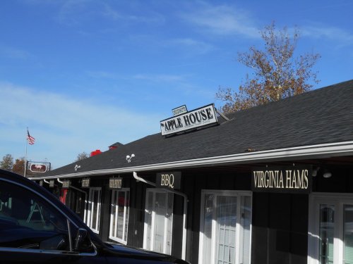 Sign for "Apple House" on a building with a clear blue sky and an American flag in the background.