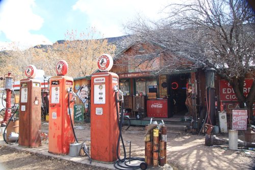 Vintage gas station with old pumps, rustic wooden building, and various retro signs in a rural setting.