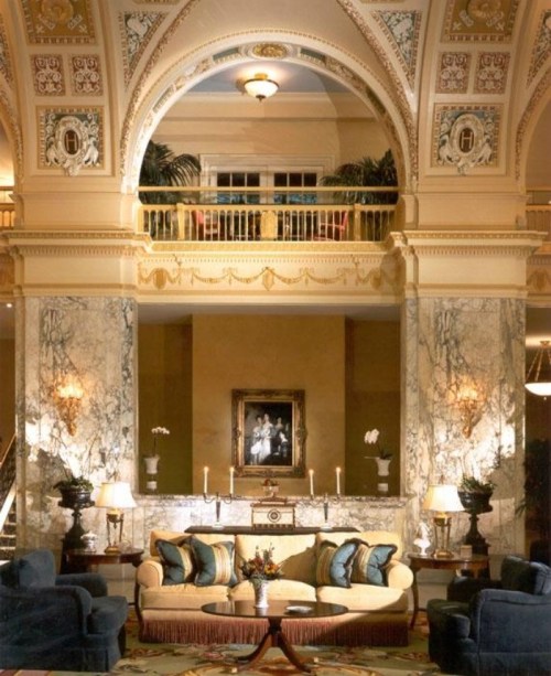 Luxurious hotel lobby with marble columns, elegant furniture, and ornate ceiling details, creating a sophisticated atmosphere.