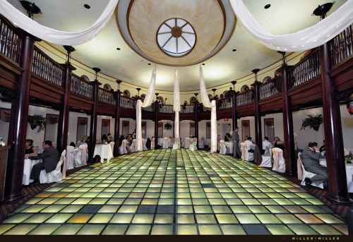Elegant banquet hall with a glass tile floor, featuring guests dining at tables surrounded by decorative drapery.