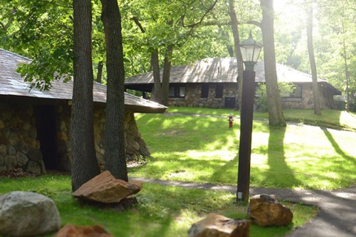 A serene outdoor scene featuring stone buildings surrounded by trees and sunlight filtering through the leaves.
