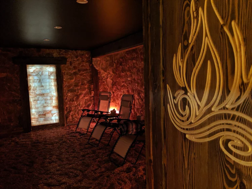A tranquil spa room with stone walls, reclining chairs, and soft lighting, creating a relaxing atmosphere.
