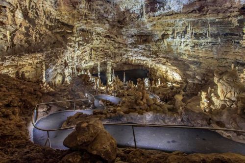 A winding path through a stunning cave with illuminated rock formations and stalactites.