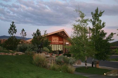 Buffalo Bill Center of the West building surrounded by greenery and trees under a cloudy sky.