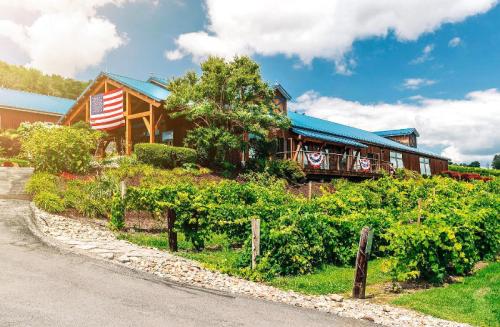 A rustic building with a blue roof, surrounded by lush vineyards and decorated with American flags.