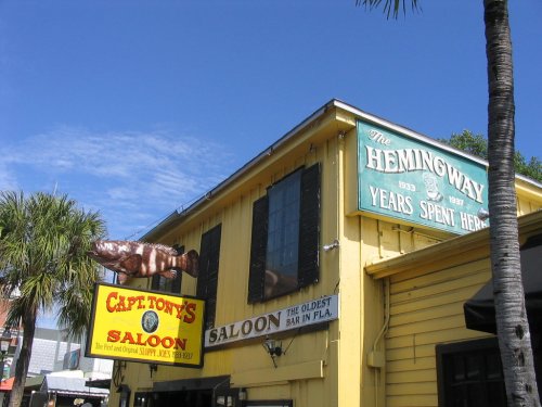 Colorful signs for Captain Tony's Saloon and The Hemingway, set against a clear blue sky and palm trees.