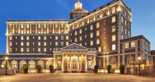 Elegant hotel exterior at dusk, featuring brick architecture and illuminated windows.
