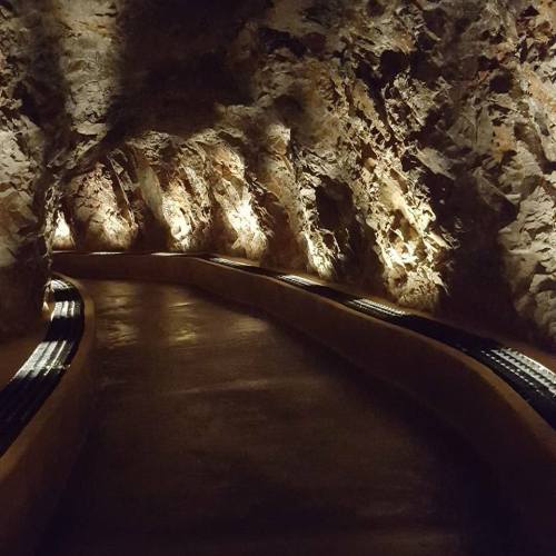 A dimly lit cave pathway with rocky walls and soft lighting along the edges, creating a mysterious atmosphere.