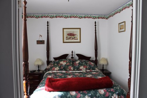 Cozy bedroom with a floral-patterned bedspread, four-poster bed, and decorative lamps on nightstands.