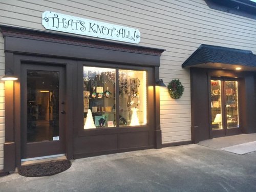Exterior view of a shop named "That's Knot All," featuring large windows displaying various items and a festive wreath.