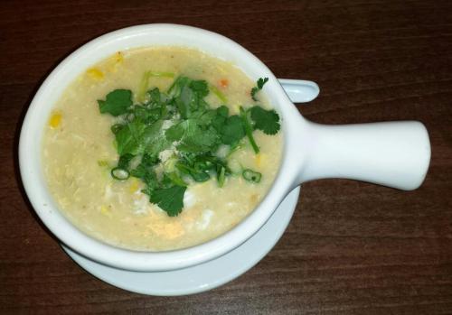 A bowl of creamy soup topped with fresh cilantro and green onions, served on a white plate.