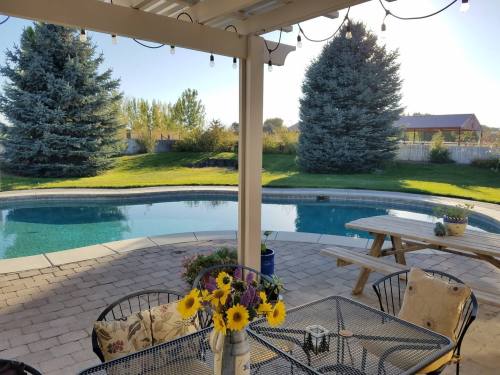 A serene backyard view featuring a pool, picnic table, and vibrant flowers under a clear blue sky.