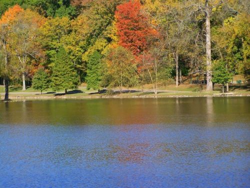 A serene lake surrounded by vibrant autumn foliage reflecting on the water's surface.
