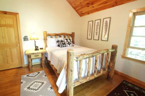 Cozy bedroom with a log bed, patterned bedding, wooden accents, and nature-themed wall art.