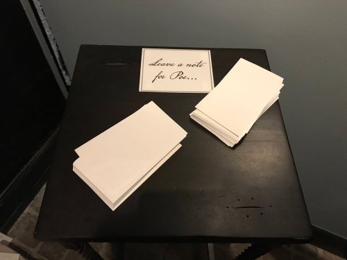 A black table with a sign that says "Leave a note for Pee" and two stacks of blank note cards.