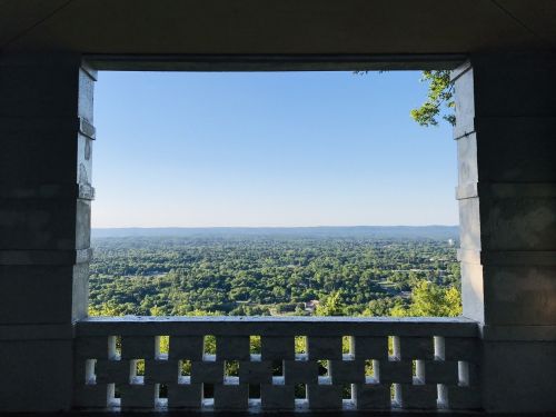 A scenic view of lush green hills and a clear blue sky framed by a stone archway.
