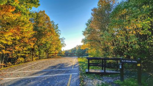 A scenic view of Old Indian Trail, lined with colorful autumn trees under a clear blue sky.