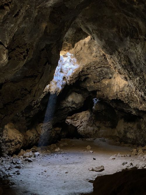A dimly lit cave interior with rocky walls and a beam of light illuminating the space.