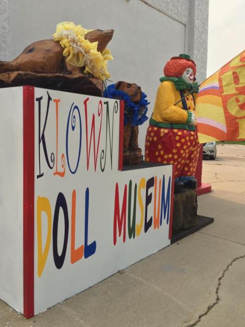 Colorful sign for the Klown Doll Museum, featuring clown and animal sculptures outside the building.