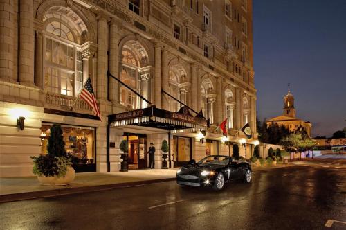 Elegant hotel entrance at night with a luxury car parked outside, featuring grand architecture and illuminated signage.