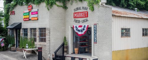 A charming market building with a welcoming entrance, decorated with patriotic bunting and colorful signage.