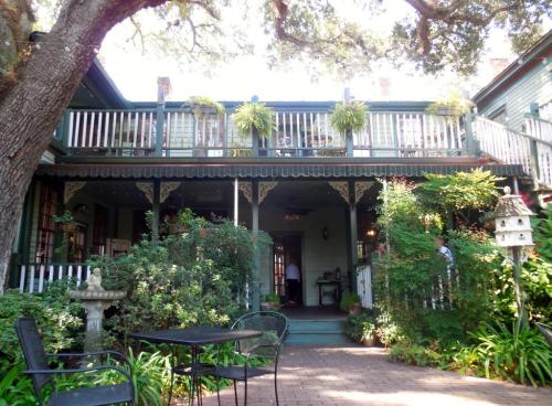 A charming two-story house with a porch, surrounded by greenery and a small garden, inviting and cozy atmosphere.