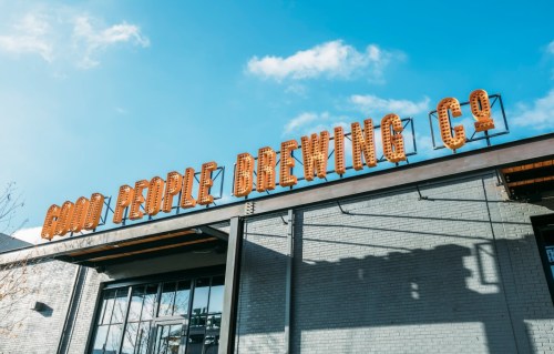 Sign for Good People Brewing Co. on a brick building under a clear blue sky.