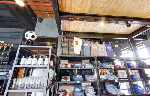 A display of t-shirts and merchandise on shelves in a modern retail space, with a soccer ball hanging above.