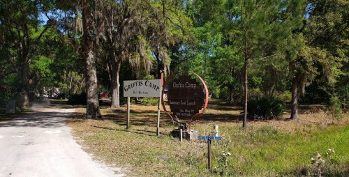 Signage for Griffis Camp, surrounded by trees and greenery, indicating a recreational area.