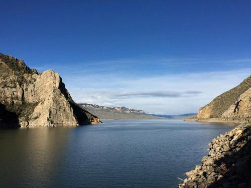 A serene lake surrounded by rocky cliffs and mountains under a clear blue sky.