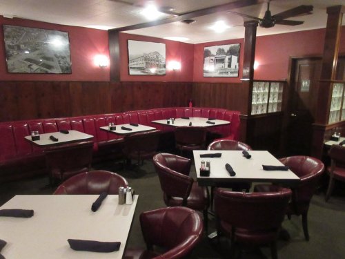 Cozy restaurant interior with red booths, white tables, and vintage black-and-white photos on the walls.