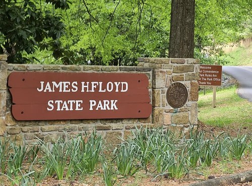 Sign for James H. Floyd State Park, featuring stone structure and greenery in the background.