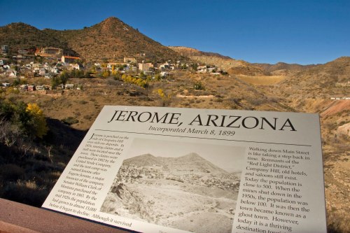 A historical sign about Jerome, Arizona, with a mountainous landscape and town in the background.