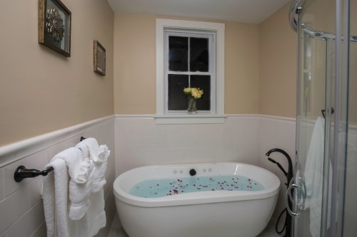A cozy bathroom featuring a freestanding tub filled with water and flower petals, with towels neatly arranged nearby.