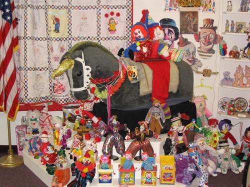A colorful display of clown dolls and toys, featuring a large stuffed horse adorned with clown decorations.