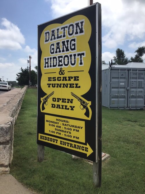Sign for Dalton Gang Hideout and Escape Tunnel, open daily with hours listed for Monday to Saturday and Sunday.