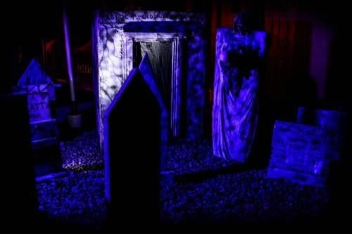 A spooky graveyard scene with tombstones and a ghostly figure, illuminated by eerie blue light.