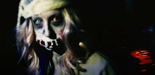 A haunting figure with pale skin, dark eyes, and a gruesome smile, wearing a hat and surrounded by darkness.