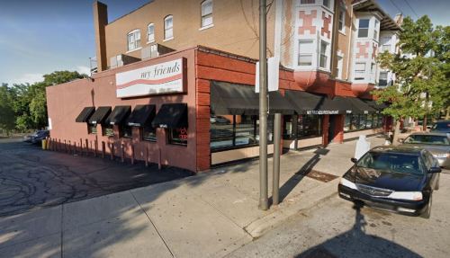 Exterior view of a restaurant named "my friends," featuring large windows and outdoor seating, located on a street corner.