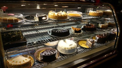 A display case filled with various cakes, including cheesecakes, chocolate cakes, and layered desserts.