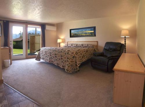 Cozy hotel room with a large bed, recliner, wooden furniture, and patio doors leading to an outdoor area.