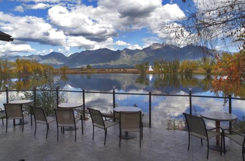 Scenic view of mountains and a lake, with a patio featuring tables and chairs in the foreground.