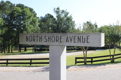Signpost reading "North Shore Avenue" in a park-like setting with trees and a gravel path.