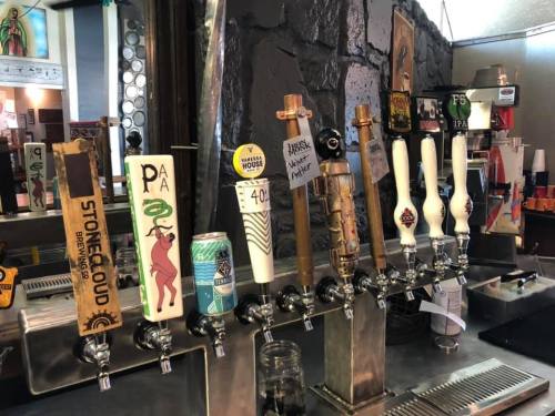 A row of beer taps featuring various craft beer brands and styles in a bar setting.