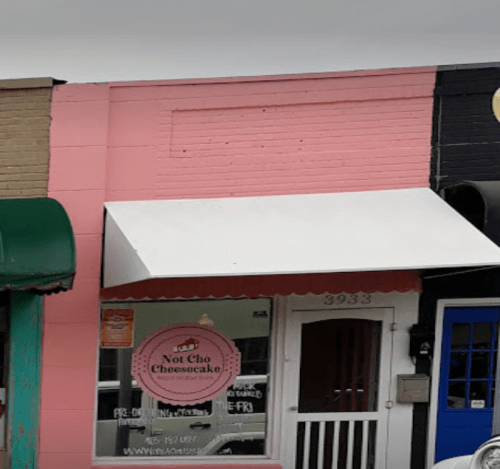 A storefront with a pink and black exterior, featuring a sign for "Not Cho Cheesecake" and a white awning.