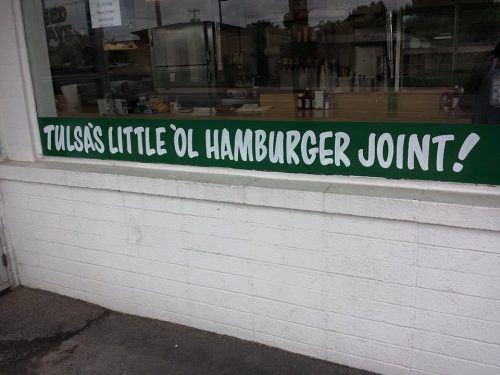 Sign on a restaurant window reads "Tulsa's Little Ol' Hamburger Joint!" in bold green letters.