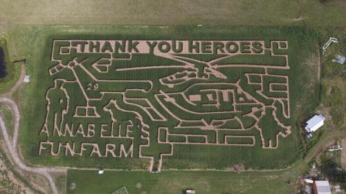 Aerial view of a corn maze featuring "Thank You Heroes," a helicopter, and farm-themed designs.