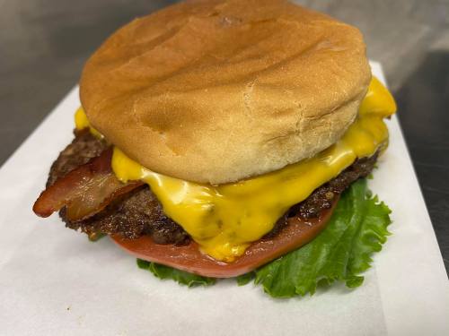 A juicy cheeseburger with bacon, melted cheese, lettuce, and tomato, served on a soft bun.